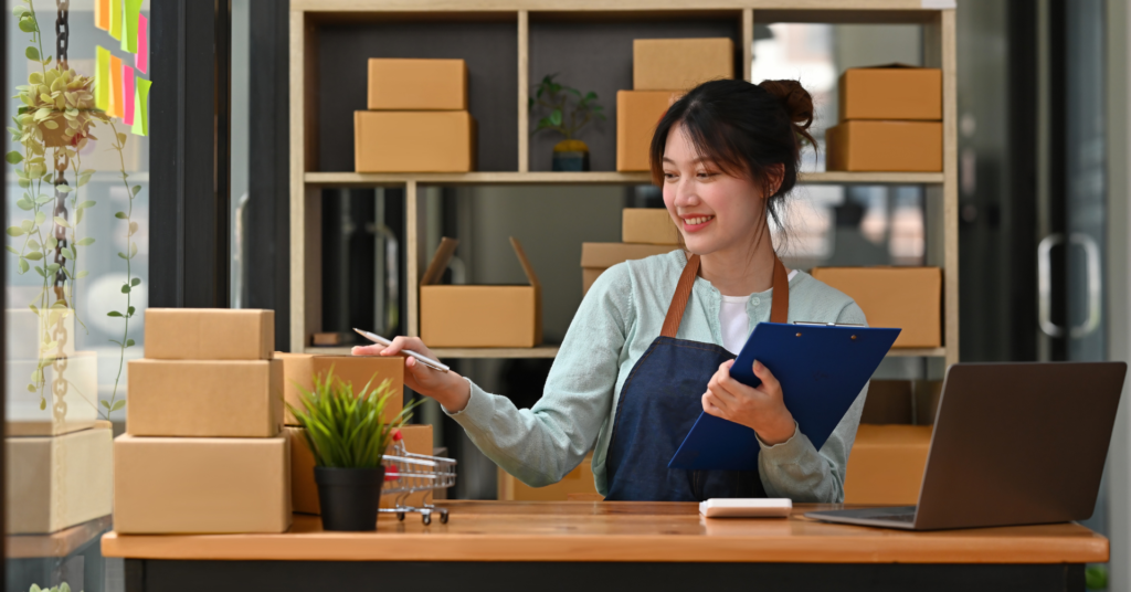 Small business store worker smiling at desk with growth chart, representing efficient growth from startup to scale in a flex space.